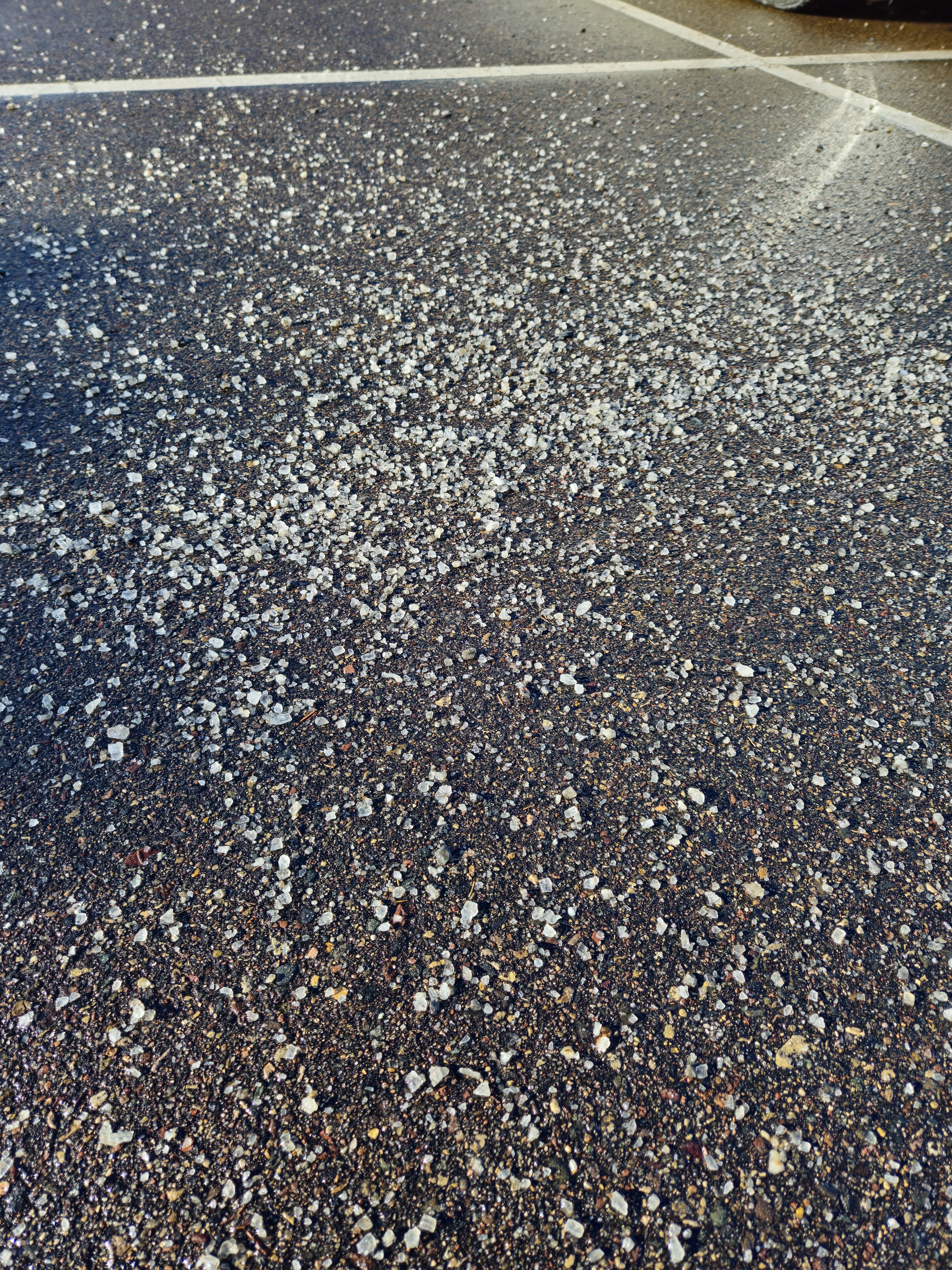 A large amount of de-icing salt on a concrete parking space.
